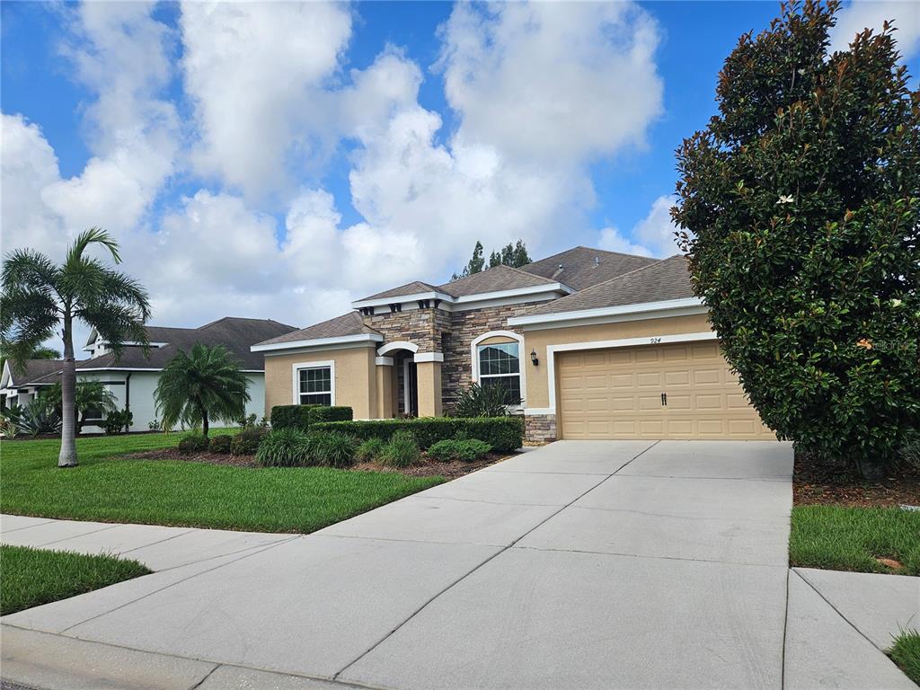 A single-story house with a stone facade, tan stucco walls, and a two-car garage — 924 BUTTERCUP GLEN, BRADENTON, FL