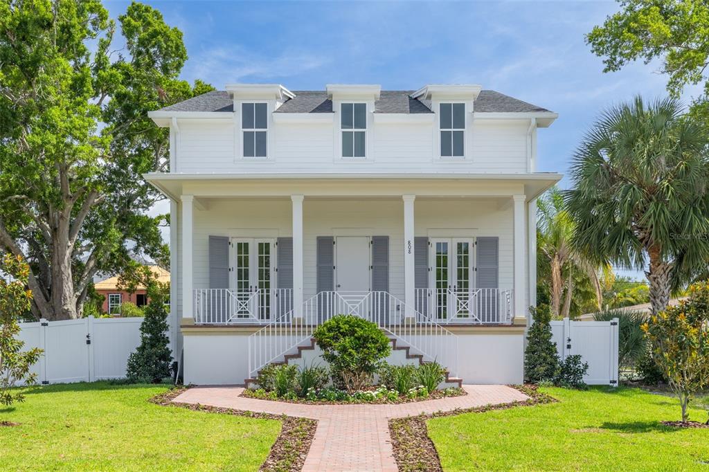 A white two-story house with a front porch, dormer windows, and a brick walkway — 808 39TH AVENUE NE, ST PETERSBURG, FL