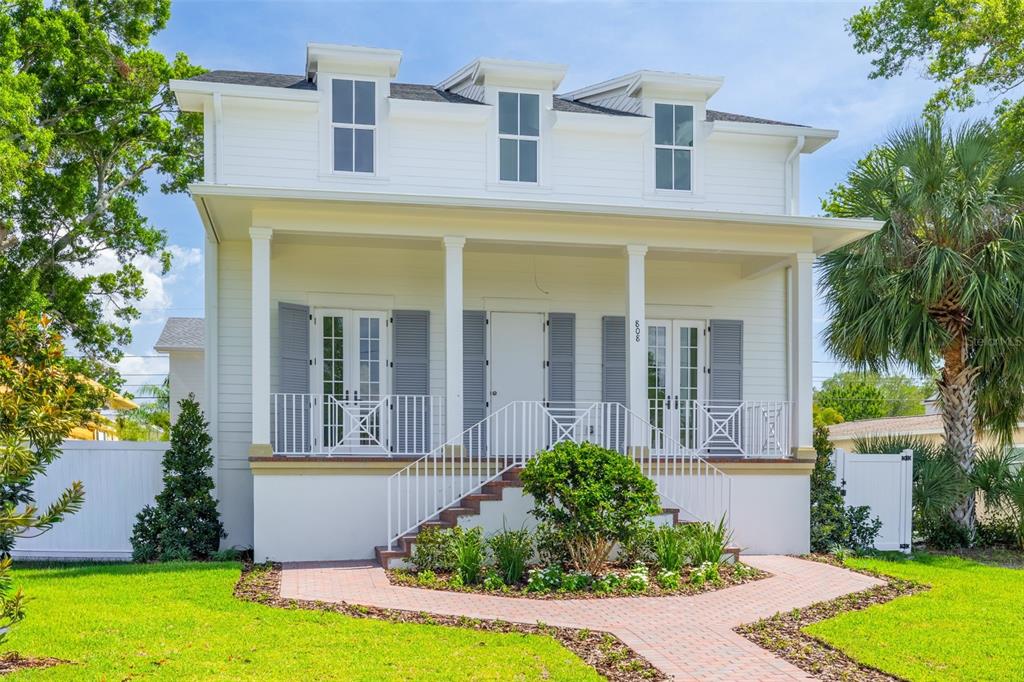 A white two-story house with a front porch, dormer windows, and a brick walkway — 808 39TH AVENUE NE, ST PETERSBURG, FL