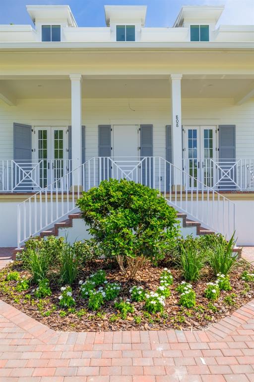 A white house with a front porch, stairs, and a landscaped garden bed — 808 39TH AVENUE NE, ST PETERSBURG, FL