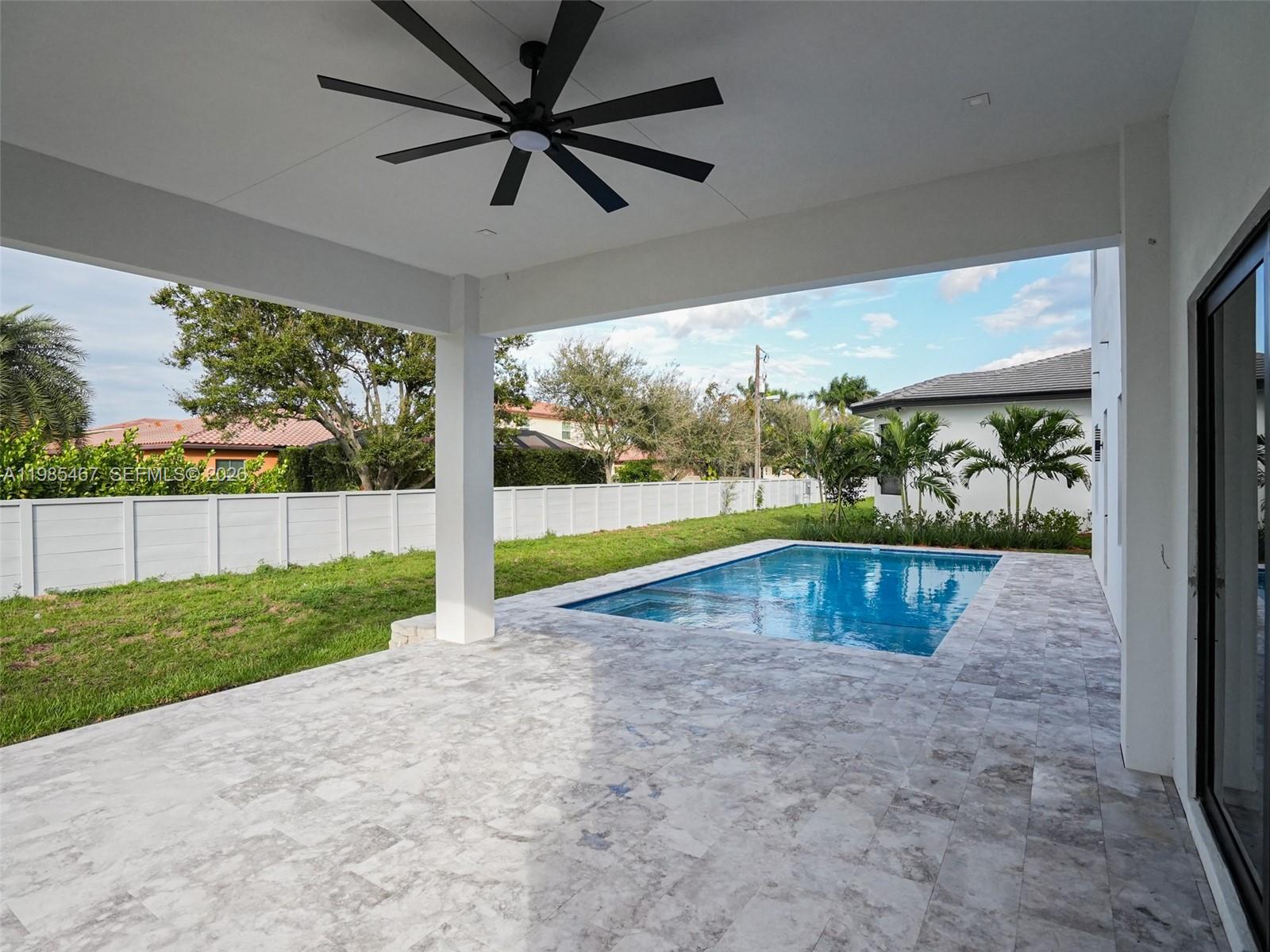 A covered patio with a ceiling fan overlooks a backyard swimming pool and lawn — 13004 Davie Oaks Dr, Davie FL 33325, DAVIE, FL