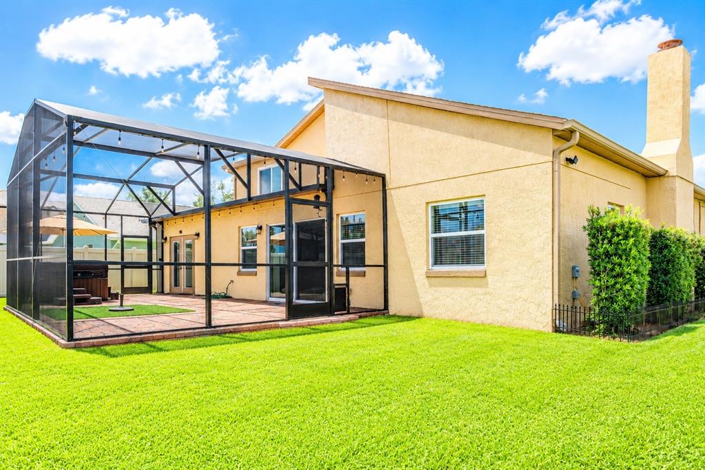 A yellow stucco house features a screened-in patio and a large green lawn — 3849 OCITA DRIVE, ORLANDO, FL