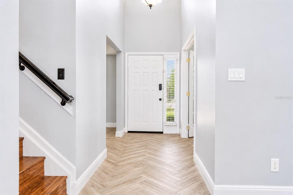 A bright entryway features a white front door, herringbone wood-look flooring, and a staircase — 3849 OCITA DRIVE, ORLANDO, FL