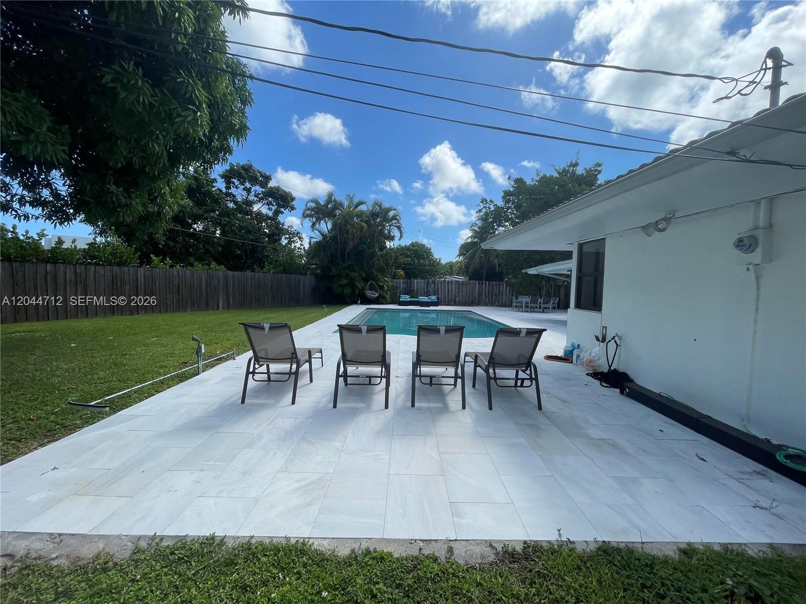 A backyard features a swimming pool, four lounge chairs, and a white patio — 2115 Alamanda Dr, North Miami FL 33181, NORTH MIAMI, FL