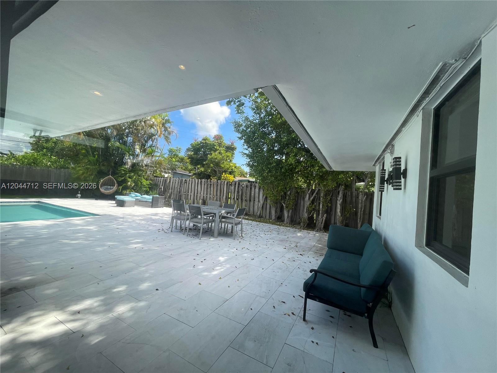 A covered patio features light-colored tile flooring, outdoor furniture, and a view of a swimming pool — 2115 Alamanda Dr, North Miami FL 33181, NORTH MIAMI, FL