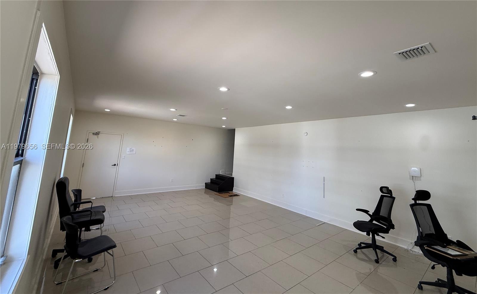 An empty office space features light-colored tile flooring, white walls, recessed lighting, and several chairs — 219 N 21st Ave, Hollywood FL 33020, HOLLYWOOD, FL