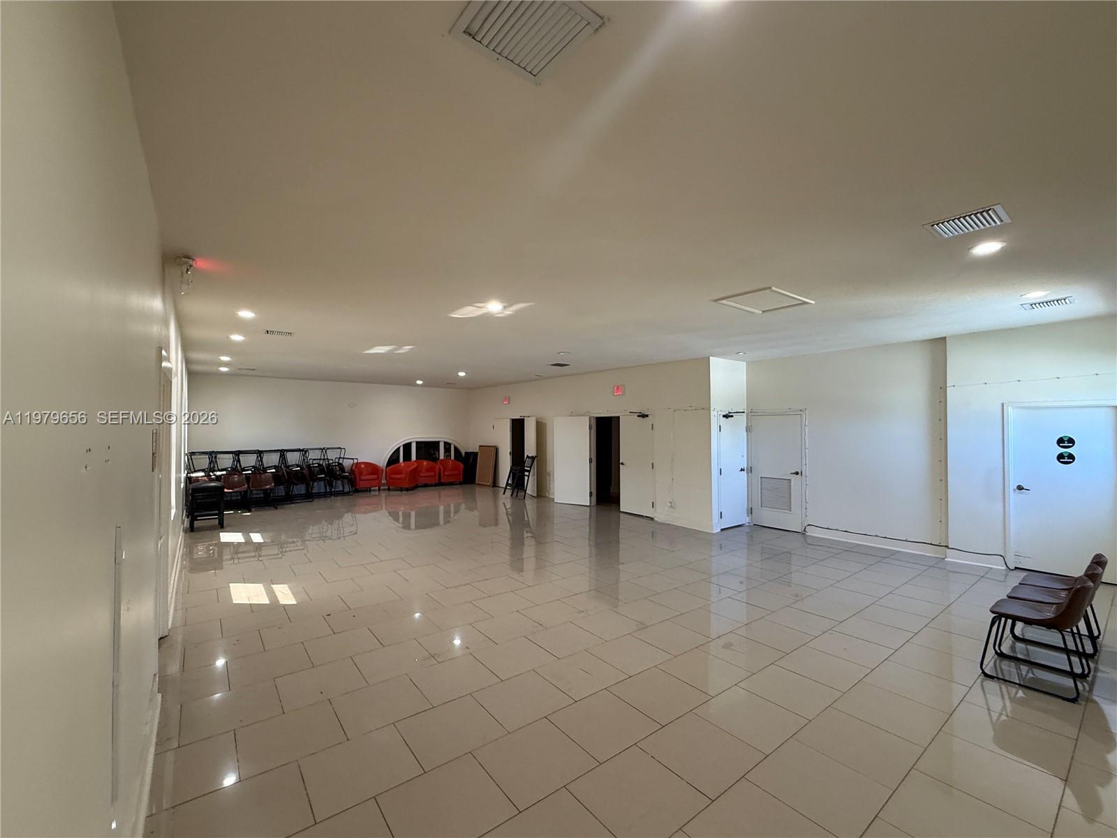 A large, empty room features light-colored tile flooring, white walls, and several scattered chairs — 219 N 21st Ave, Hollywood FL 33020, HOLLYWOOD, FL