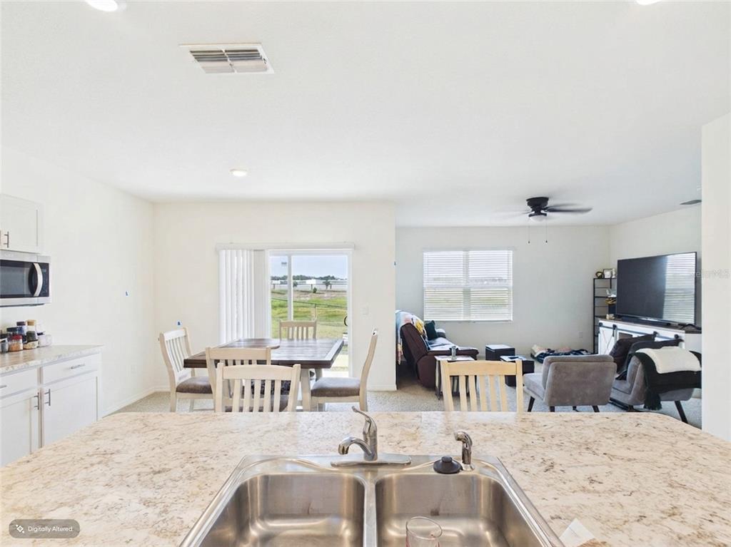 A kitchen island with a double sink overlooks an open-concept dining and living area — 804 AUBURN GROVE COURT, AUBURNDALE, FL