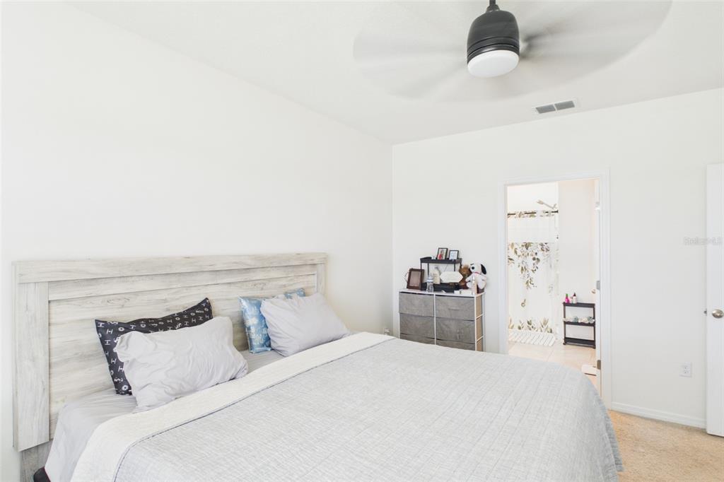 A bedroom features a light wood headboard, a gray bedspread, and an attached bathroom — 804 AUBURN GROVE COURT, AUBURNDALE, FL