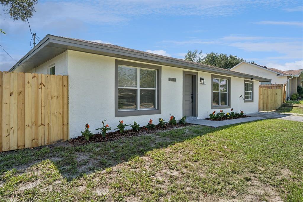 A single-story house with white stucco walls, gray trim, and a wooden fence — 2715 TIMBERLAKE AVENUE, DELTONA, FL