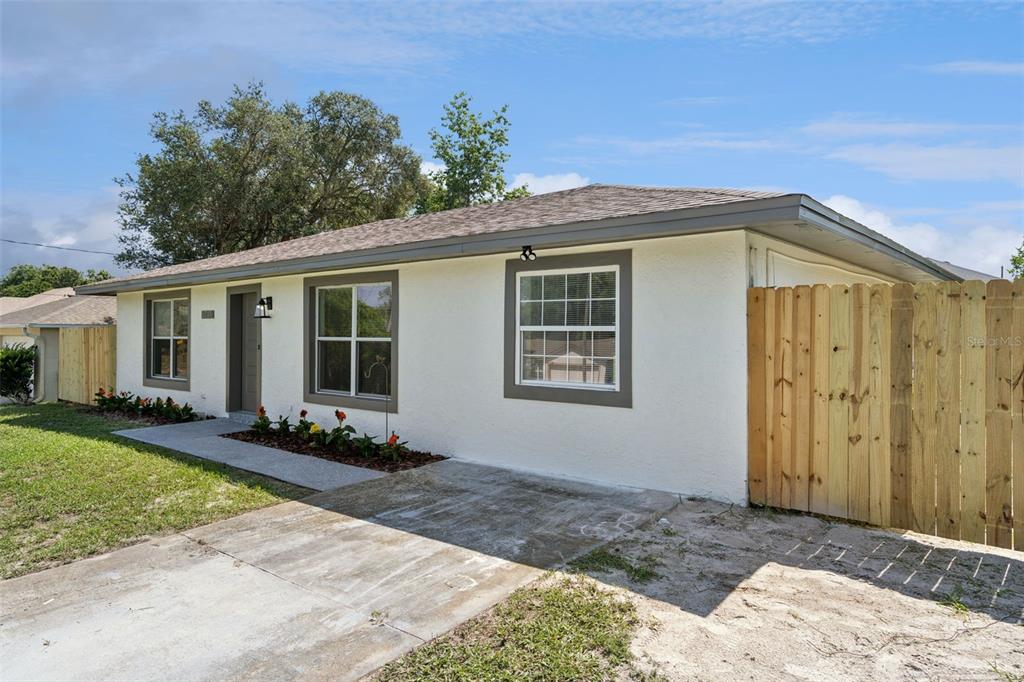 A single-story house with a white stucco exterior, grey trim, and a wooden privacy fence — 2715 TIMBERLAKE AVENUE, DELTONA, FL