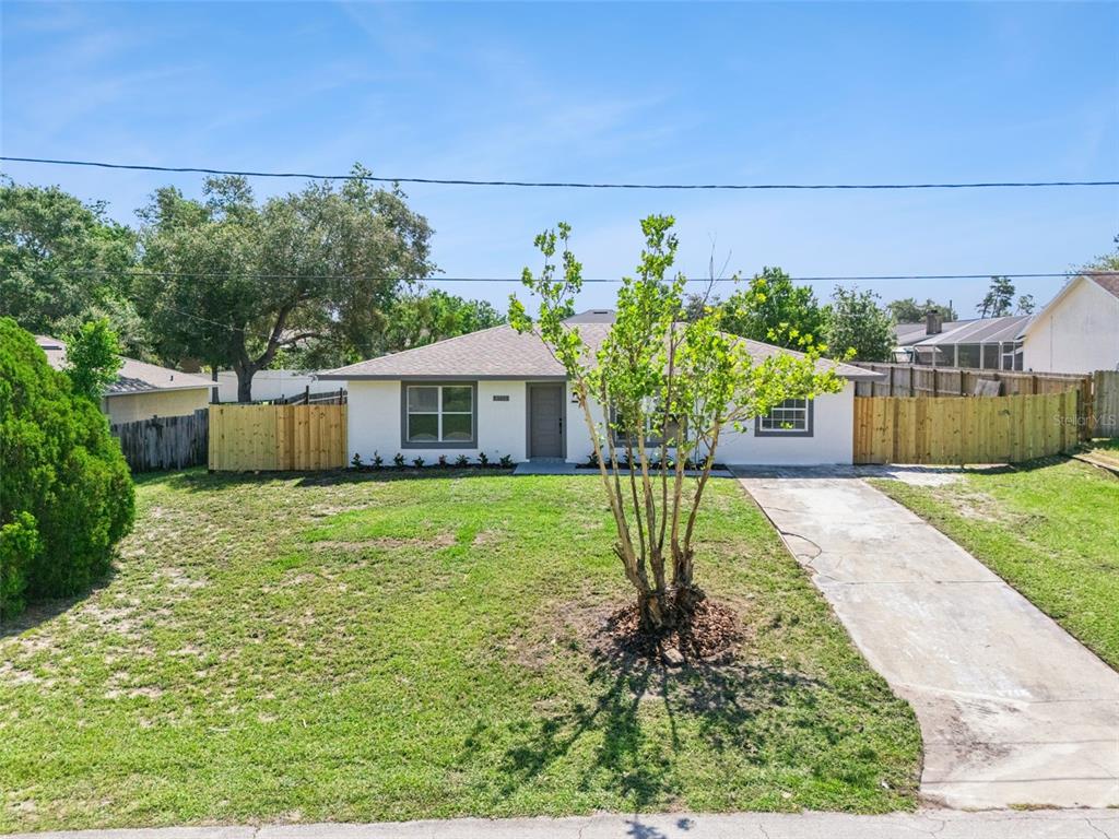 A single-story house with a white exterior, a concrete driveway, and a wooden fence — 2715 TIMBERLAKE AVENUE, DELTONA, FL