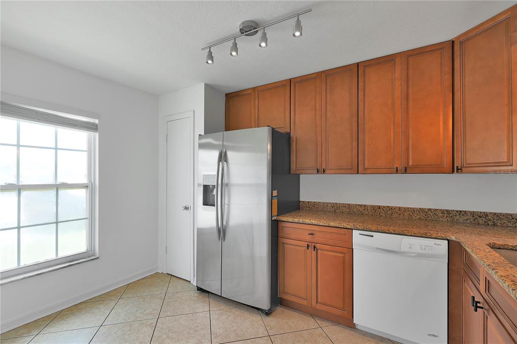 A kitchen features wood cabinets, granite countertops, stainless steel appliances, and tile flooring — 509 POLARIS LOOP UNIT 101, CASSELBERRY, FL