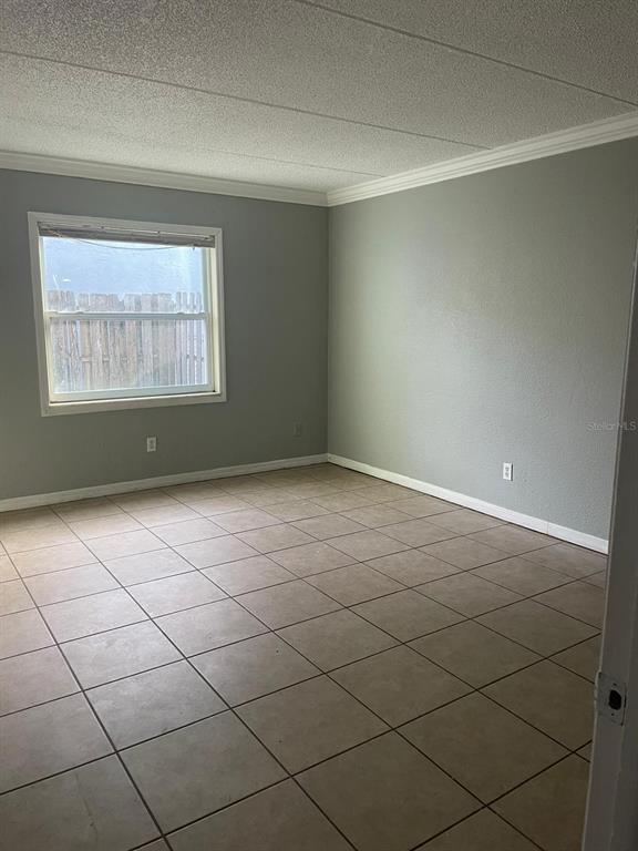 An empty room with gray walls, beige tile flooring, and a single window — 14413 AMERICANA CIRCLE UNIT 105, TAMPA, FL