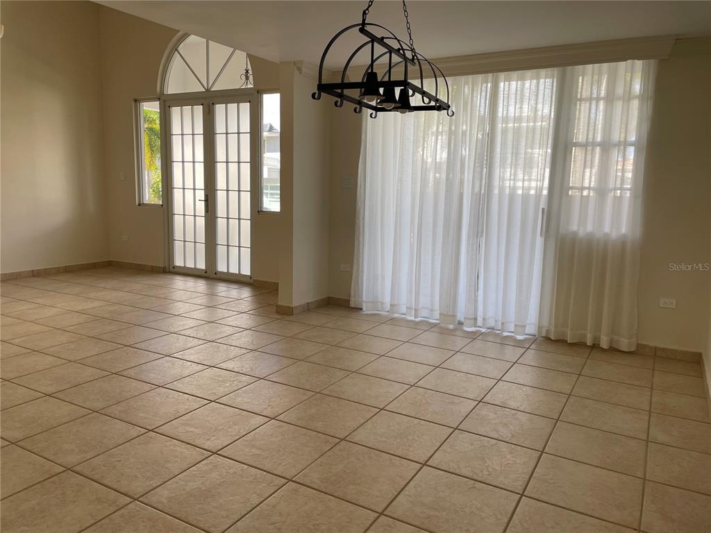 A dining room with tile flooring, a metal chandelier, and large glass sliding doors — Palma Real COCO PLUMOSA, GUAYNABO, PR