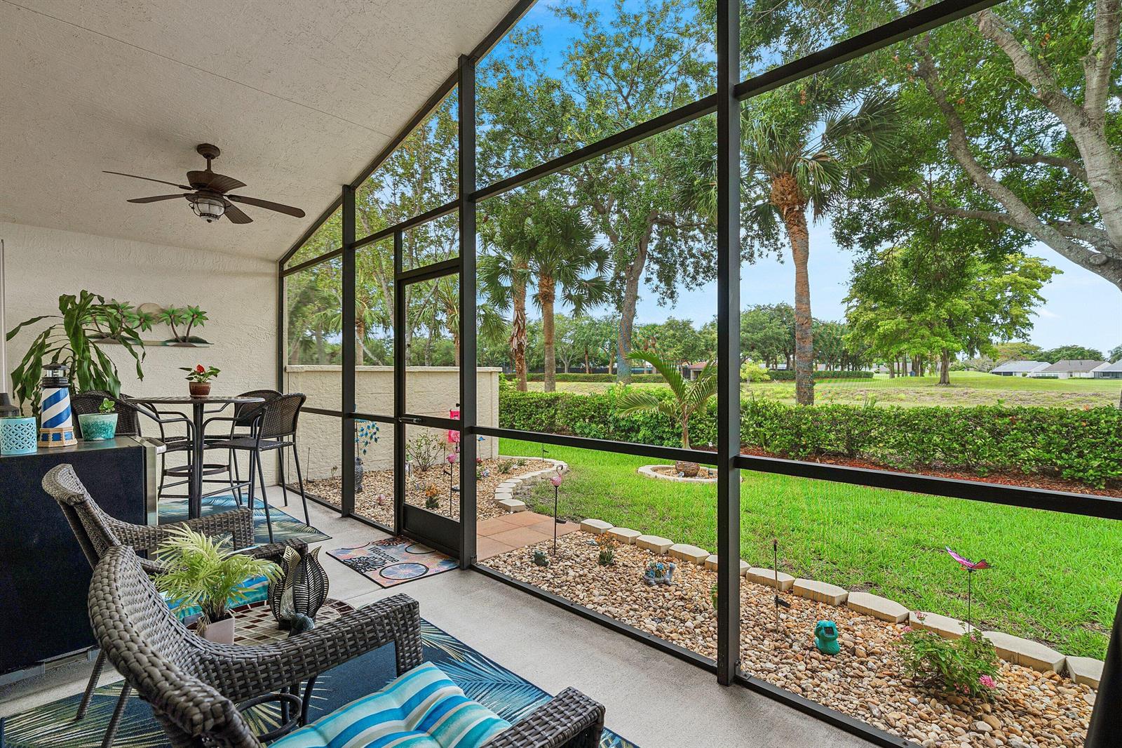 A screened-in patio with wicker furniture overlooks a grassy yard with trees and landscaping — 12095 Roma Road, Boynton Beach FL 33437, BOYNTON BEACH, FL