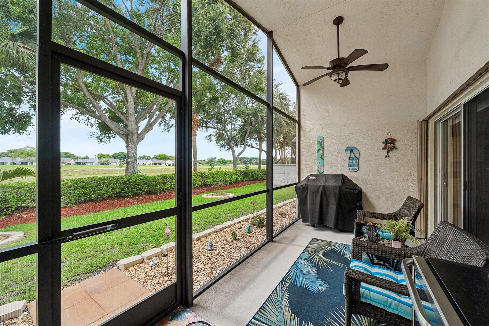 A screened-in patio features wicker furniture, a ceiling fan, and a view of a lawn — 12095 Roma Road, Boynton Beach FL 33437, BOYNTON BEACH, FL