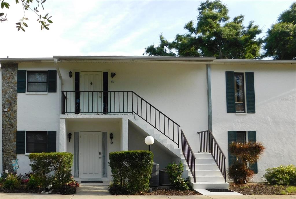 A two-story white building features an exterior staircase leading to an upper-level balcony — 5400 34TH STREET W UNIT L5, BRADENTON, FL