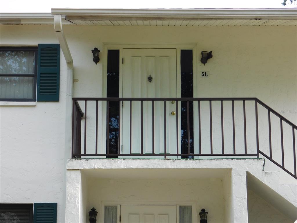An exterior view of a second-floor apartment entrance with a balcony and metal railing — 5400 34TH STREET W UNIT L5, BRADENTON, FL