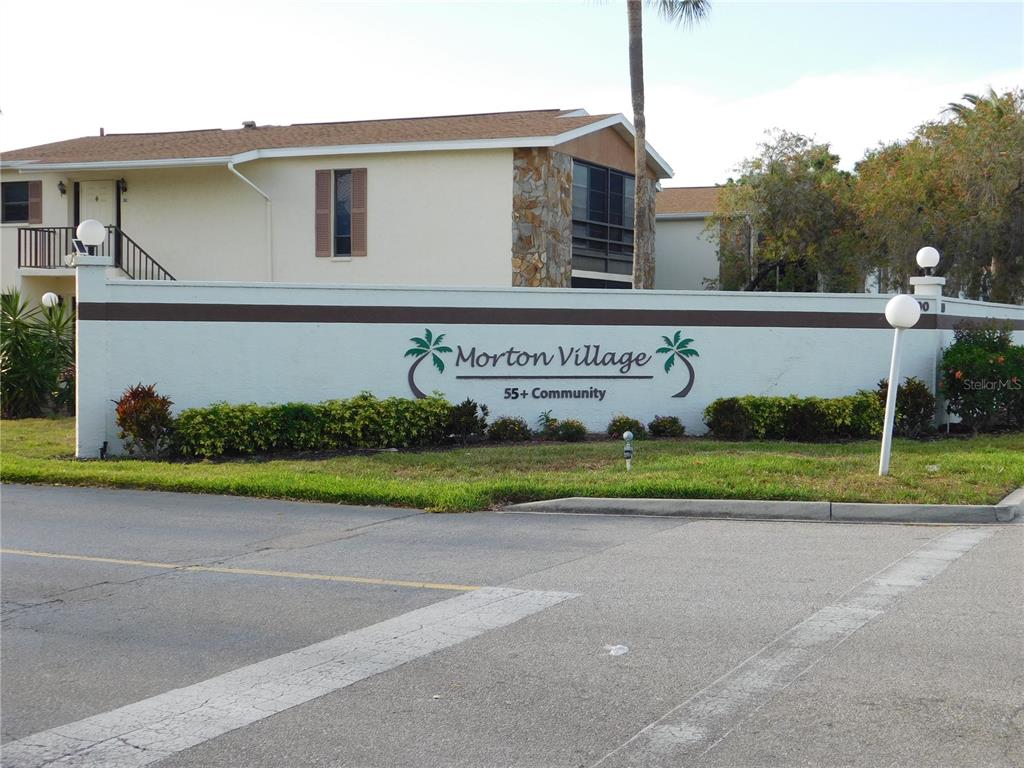 A white wall with the Morton Village 55+ Community sign stands before a two-story building — 5400 34TH STREET W UNIT L5, BRADENTON, FL