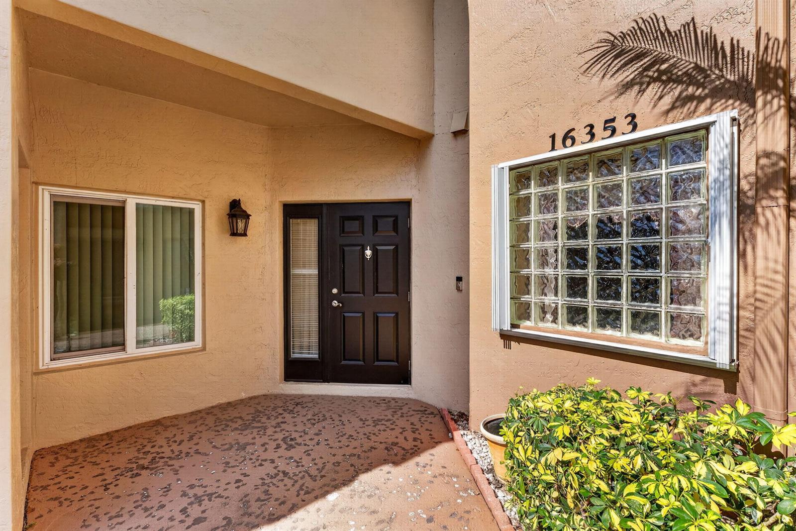The exterior entrance features a dark front door, a glass block window, and a patio — 16353 Malibu Drive # 61, Weston FL 33326, WESTON, FL