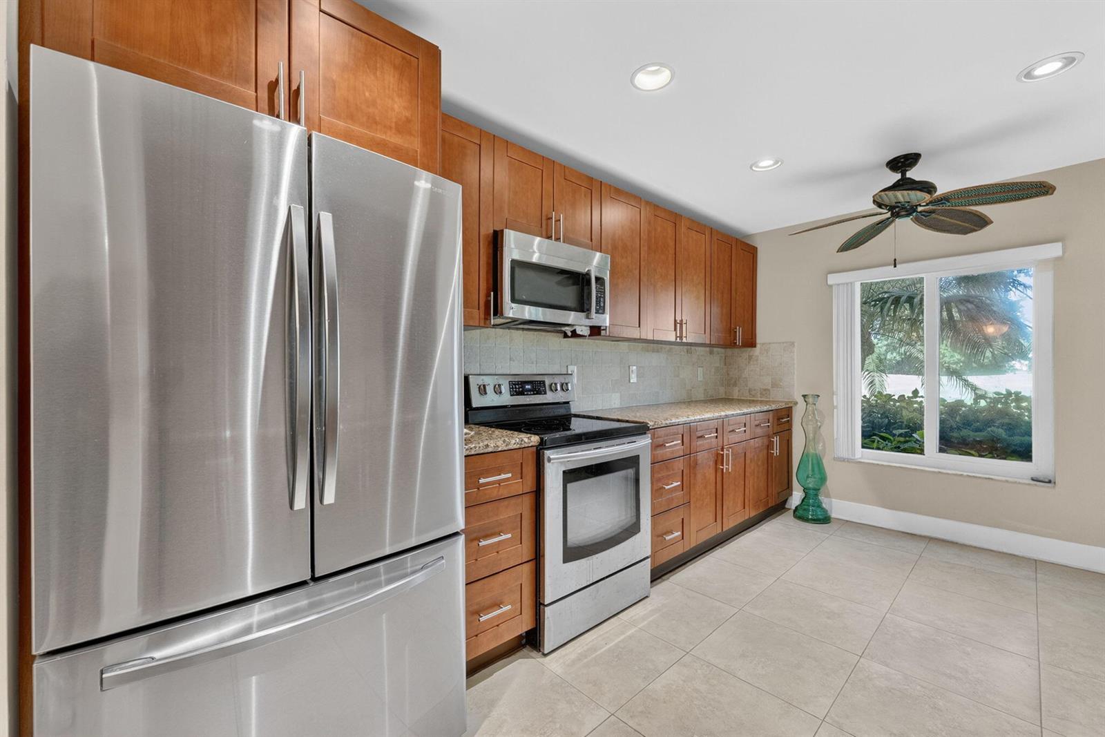 A kitchen features wood cabinets, stainless steel appliances, granite countertops, and a ceiling fan — 16353 Malibu Drive # 61, Weston FL 33326, WESTON, FL