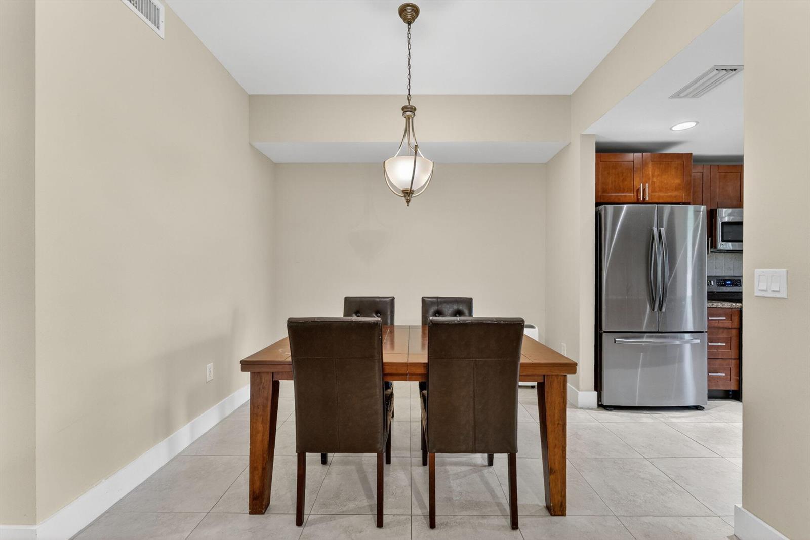 A dining area features a wooden table with four leather chairs under a pendant light — 16353 Malibu Drive # 61, Weston FL 33326, WESTON, FL