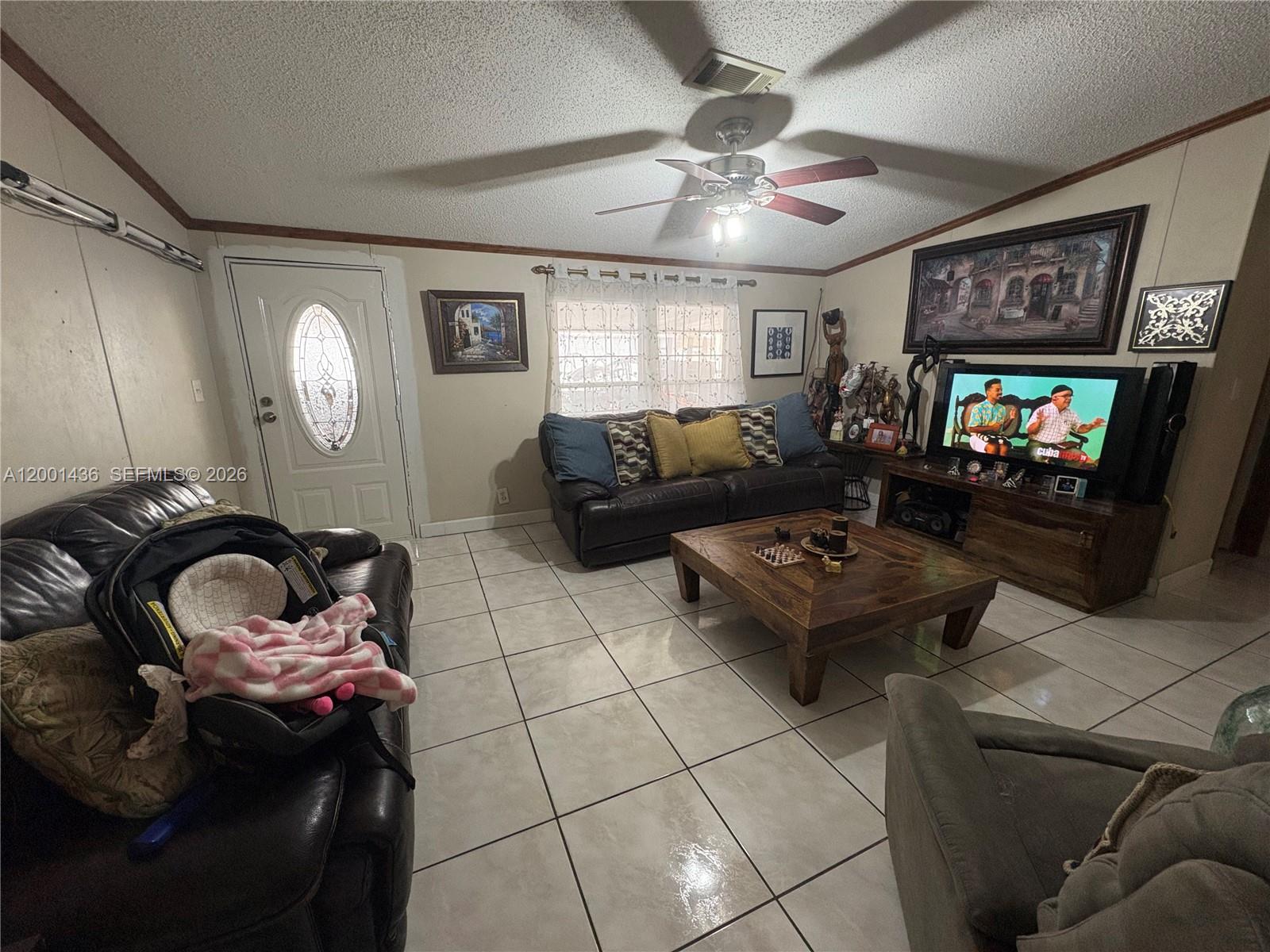 A living room features tile flooring, a ceiling fan, a leather sofa, and a television — 1110 SW 131 PL, Miami FL 33184, MIAMI, FL