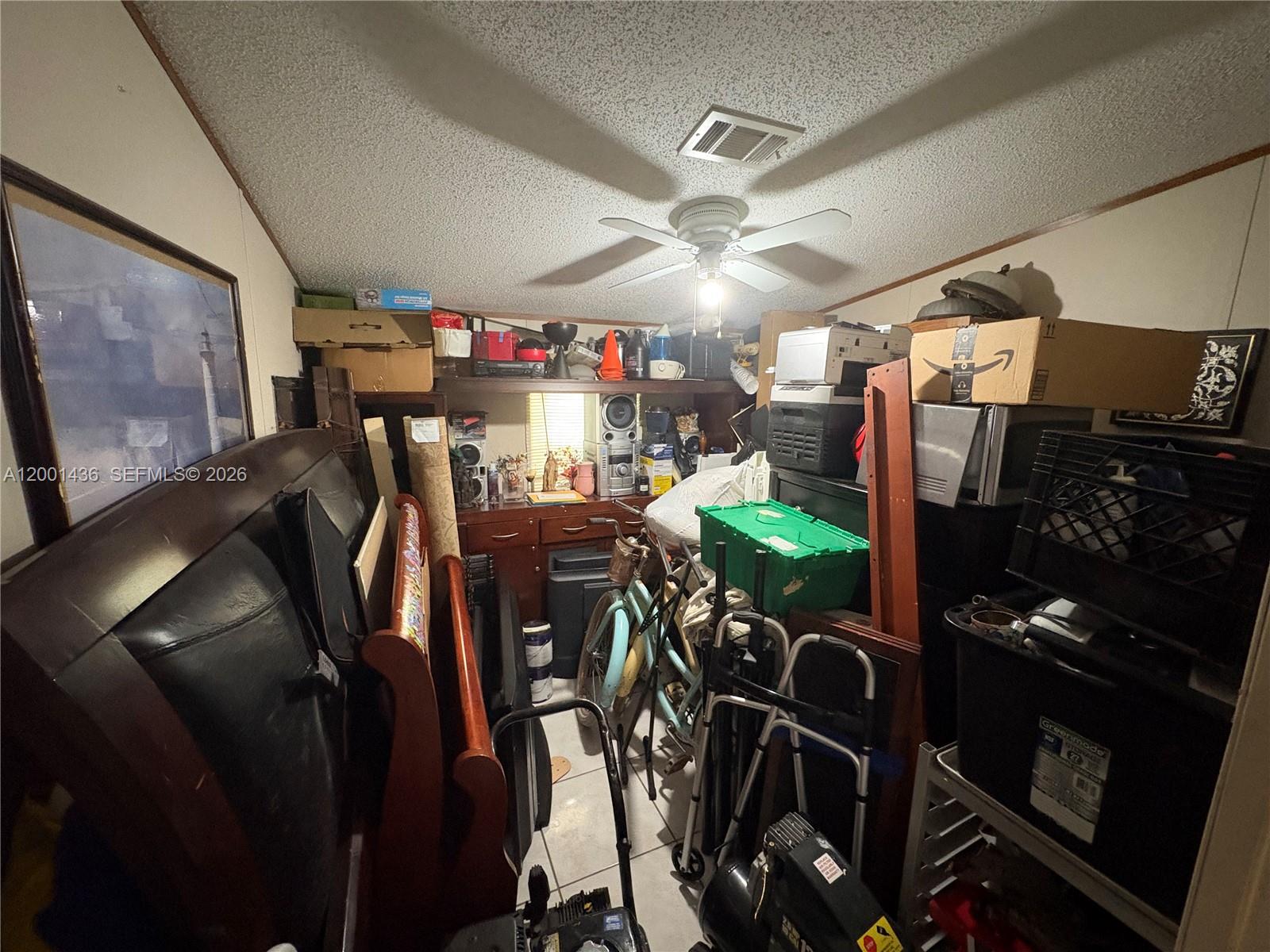 A cluttered storage room features a ceiling fan, tiled flooring, and various household items — 1110 SW 131 PL, Miami FL 33184, MIAMI, FL