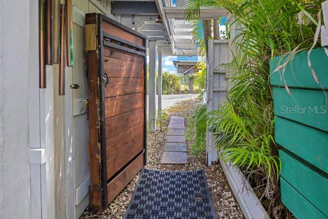 A wooden gate stands beside a walkway leading to an outdoor area with green planters — PELICAN ESTATE-PUNTAS- CARR 413 KM 3.3, RINCON, PR