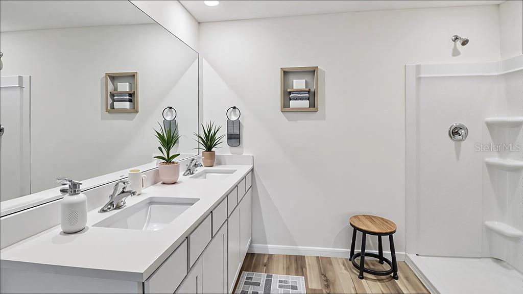 A modern bathroom features a double vanity with white countertops and a walk-in shower — 7187 SE 112TH LANE, BELLEVIEW, FL