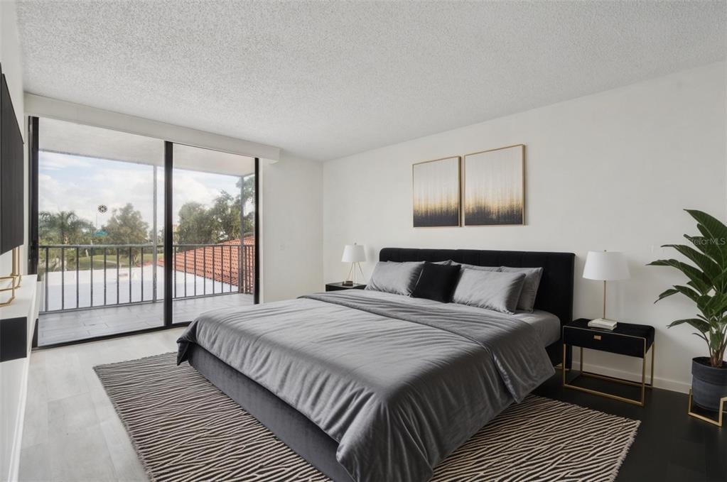 A bedroom features a bed with grey bedding, two nightstands, and a balcony with railings — 6219 PALMA DEL MAR BOULEVARD S UNIT 301, ST PETERSBURG, FL