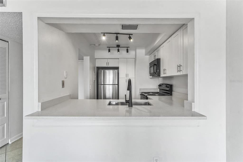 A kitchen with white cabinets, stainless steel appliances, and a quartz breakfast bar countertop — 6219 PALMA DEL MAR BOULEVARD S UNIT 301, ST PETERSBURG, FL