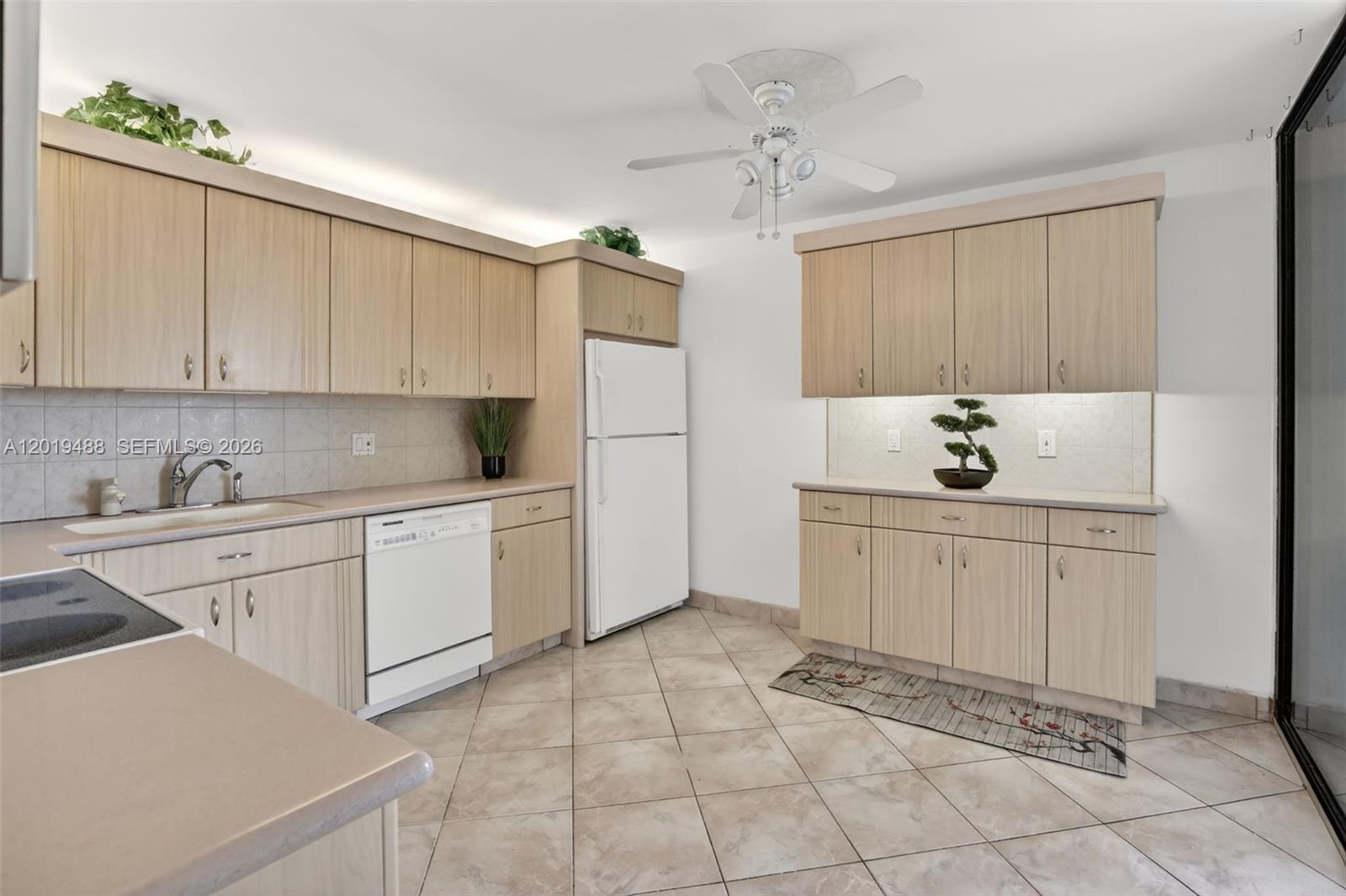 A kitchen features light wood cabinets, white appliances, tile flooring, and a ceiling fan — 2808 N 46th Ave # E654, Hollywood FL 33021, HOLLYWOOD, FL