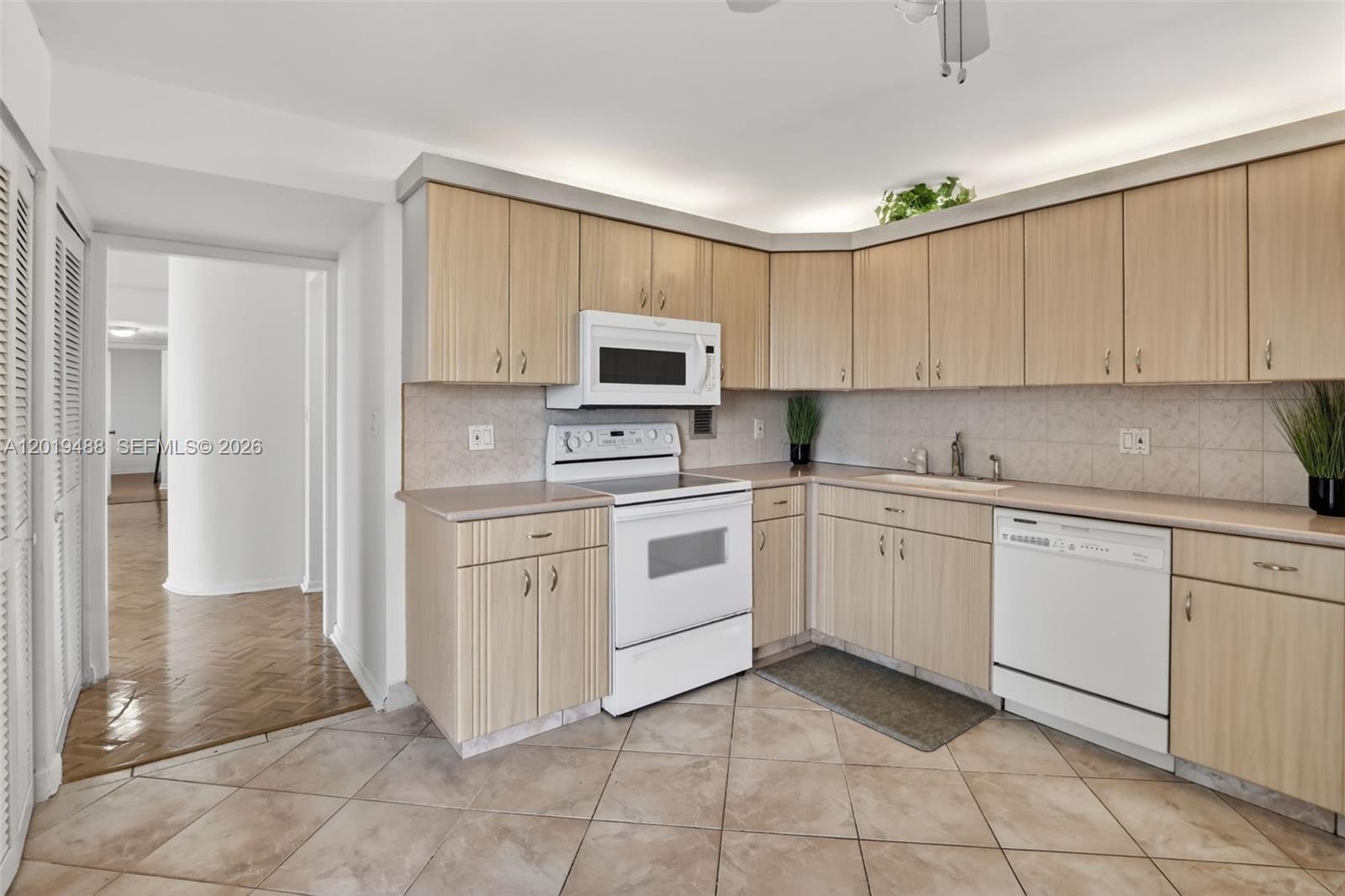 A kitchen features light wood cabinets, white appliances, and beige tile flooring — 2808 N 46th Ave # E654, Hollywood FL 33021, HOLLYWOOD, FL