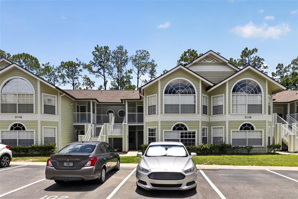 A two-story apartment building exterior with light green siding and a parking lot in front — 2016 ROYAL BAY BOULEVARD UNIT 103, KISSIMMEE, FL