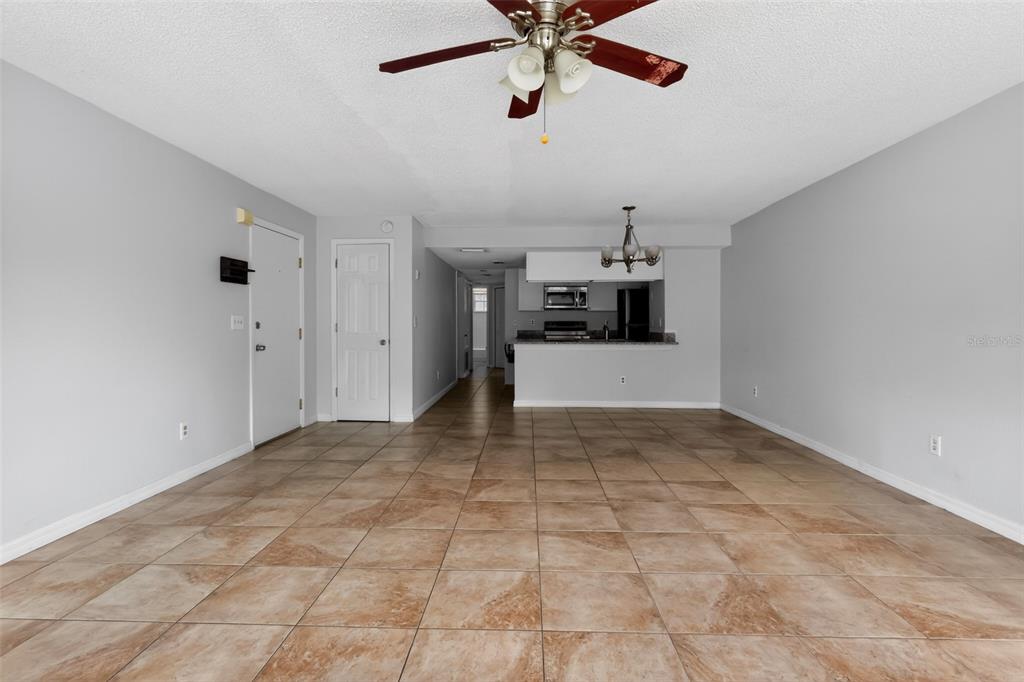 An open-concept living area features light gray walls, tile flooring, and a ceiling fan — 2016 ROYAL BAY BOULEVARD UNIT 103, KISSIMMEE, FL