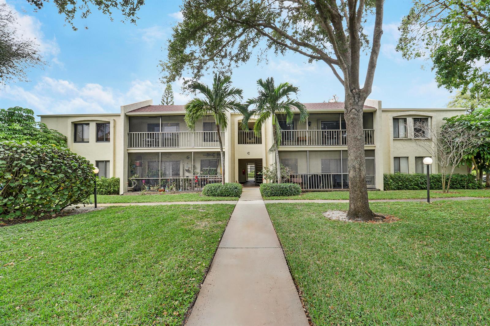 A two-story apartment building with screened balconies and a central walkway surrounded by lawn — 150 Pineview Road # C4, Jupiter FL 33469, JUPITER, FL