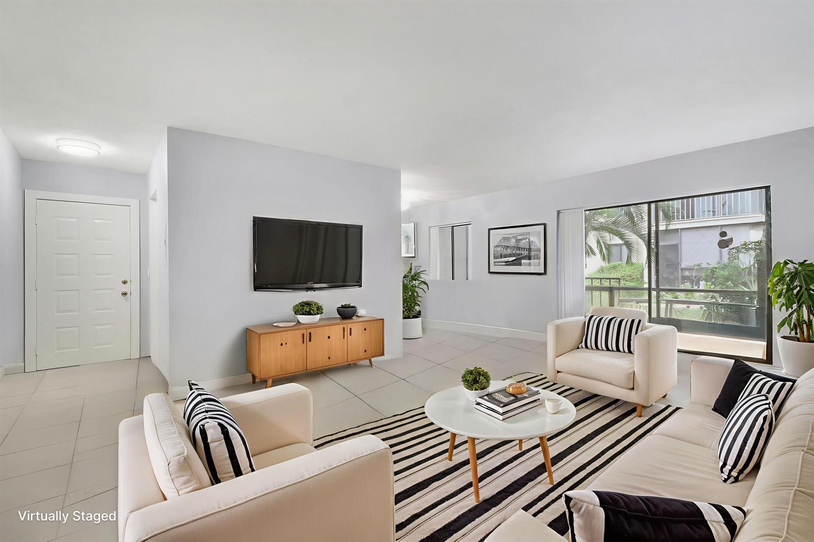 A virtually staged living room features white tile floors, a striped rug, and a sliding door — 150 Pineview Road # C4, Jupiter FL 33469, JUPITER, FL