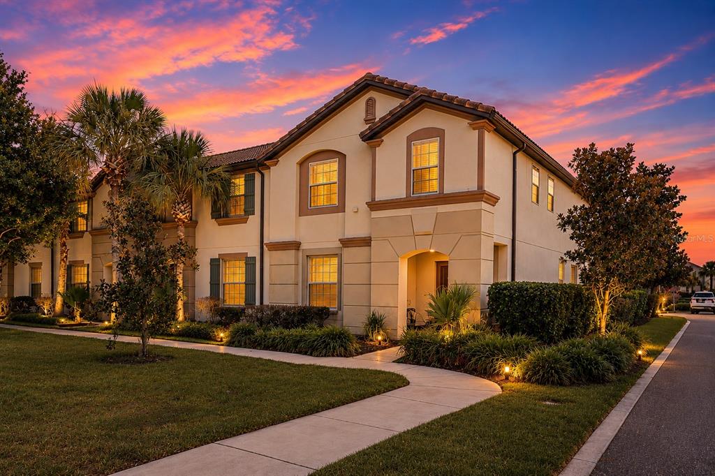 A two-story beige stucco house with a tiled roof at sunset — 1974 MAJORCA DRIVE, KISSIMMEE, FL