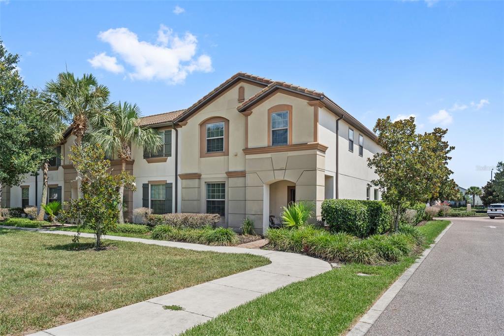 A two-story tan stucco townhouse with a tile roof and a front walkway — 1974 MAJORCA DRIVE, KISSIMMEE, FL