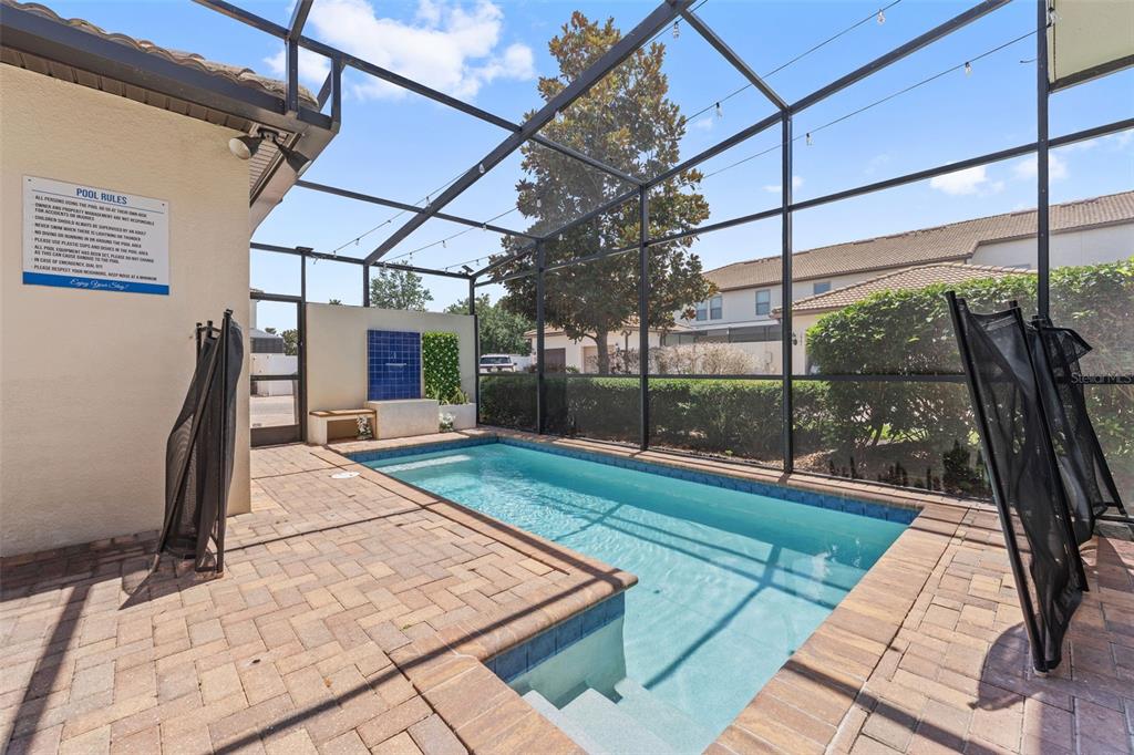 A screened-in patio features a rectangular swimming pool with a small water feature — 1974 MAJORCA DRIVE, KISSIMMEE, FL