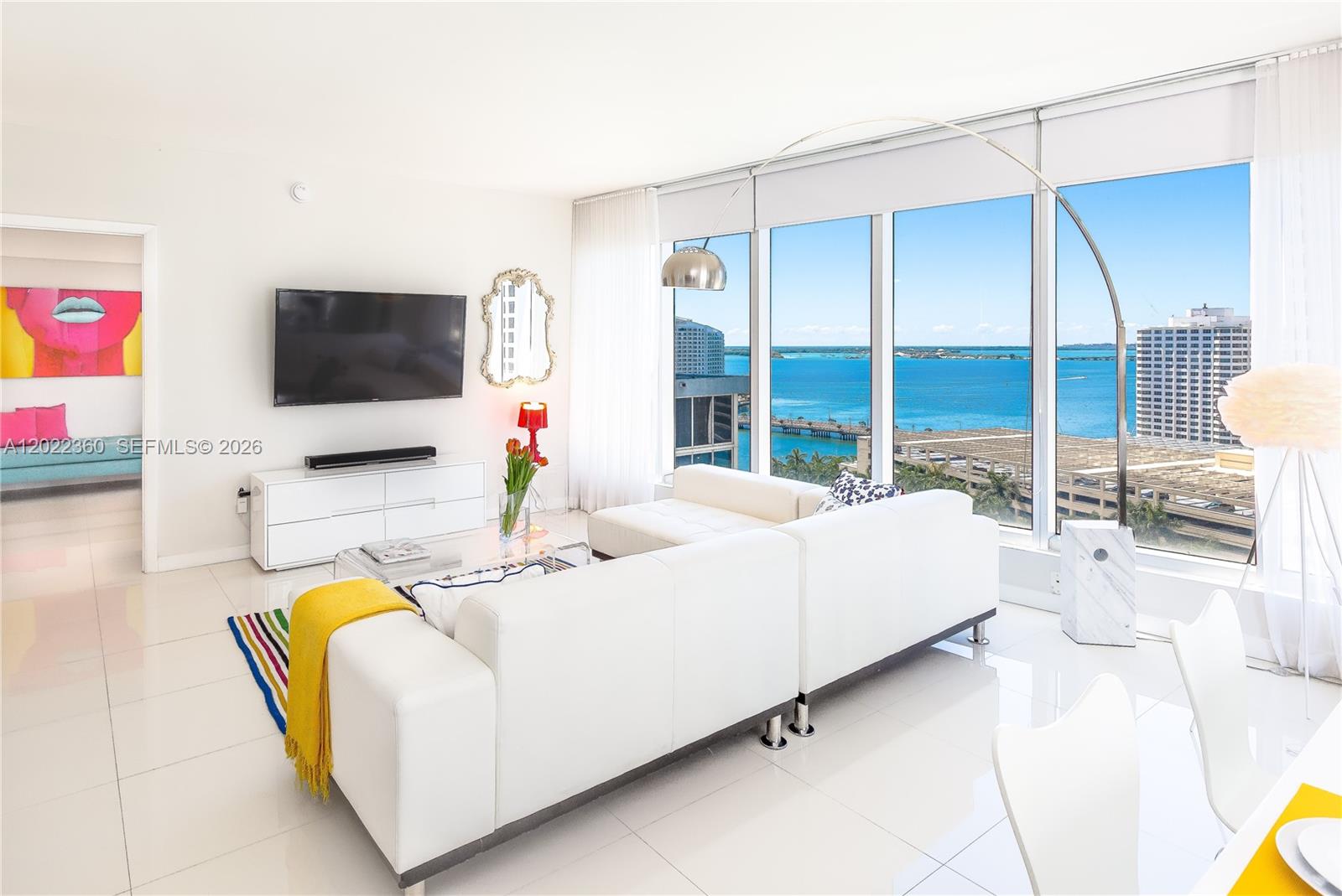 A modern living room features a white sectional sofa, a television, and floor-to-ceiling windows — MIAMI, FL