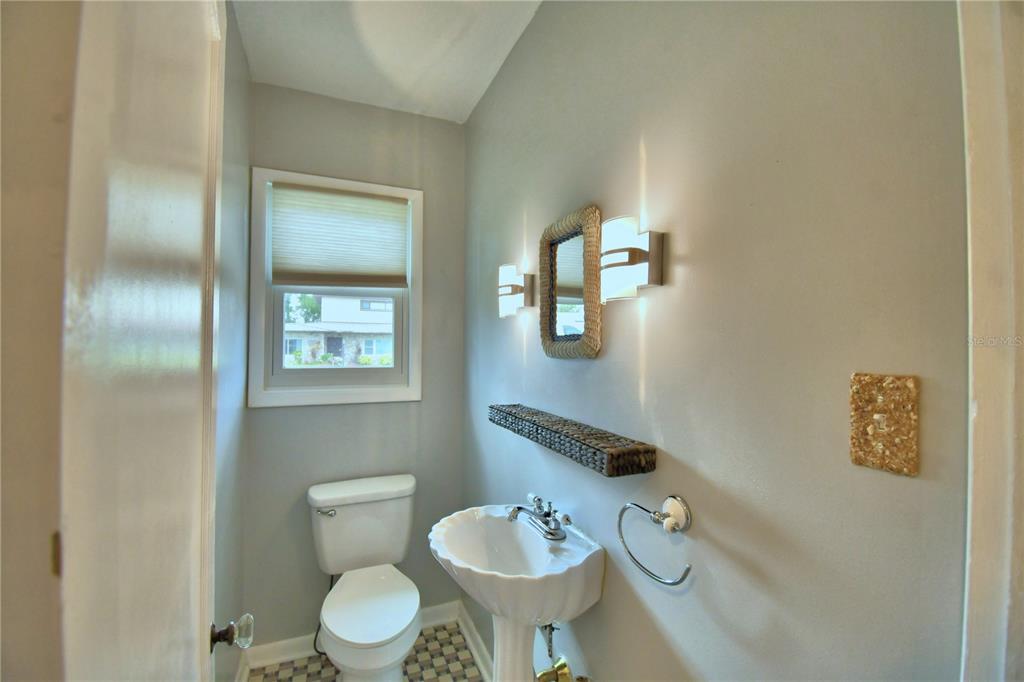 A small bathroom features a pedestal sink, a toilet, a mirror, and a window — 1620 17TH STREET NW, WINTER HAVEN, FL
