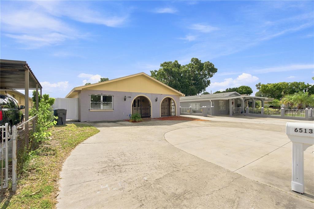 A single-story house with a concrete driveway and a large front yard — 6513 N MANHATTAN AVENUE, TAMPA, FL