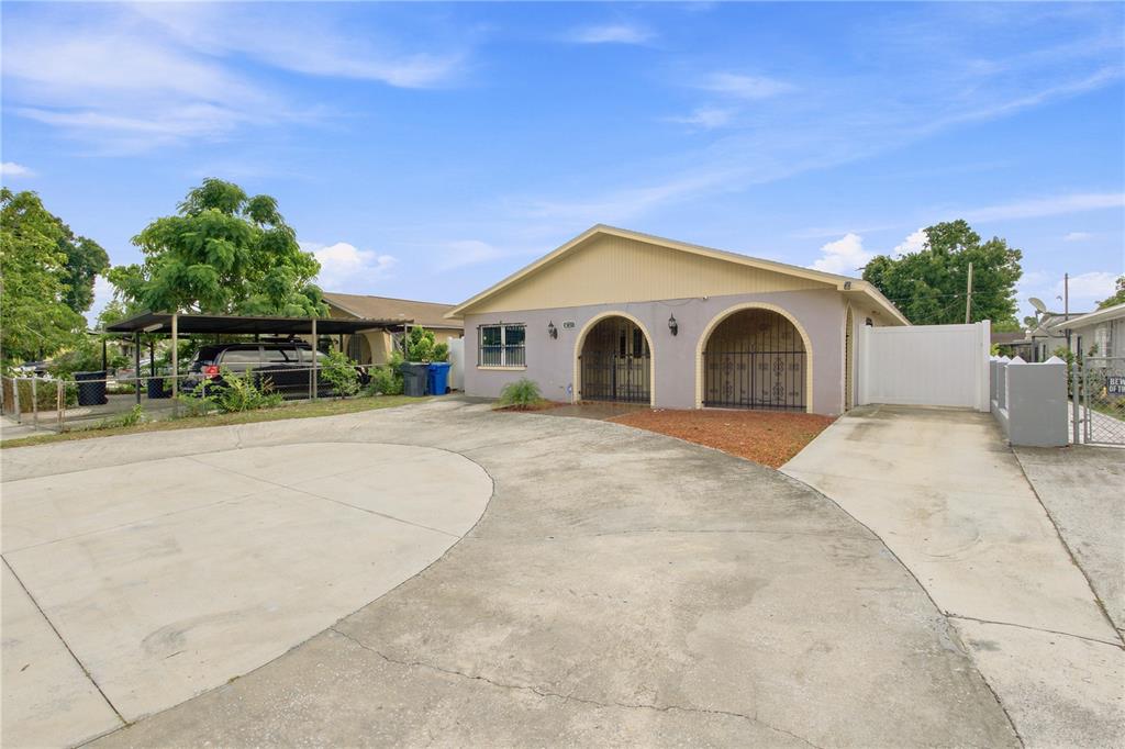 A single-story house with a beige facade, two arched entryways, and a large concrete driveway — 6513 N MANHATTAN AVENUE, TAMPA, FL