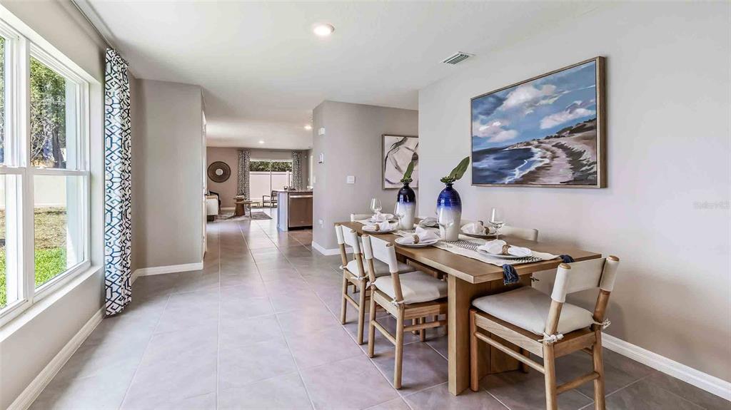 A dining area features a wooden table with six chairs and a large coastal painting — 35489 SUNFLOWER HILL DRIVE, ZEPHYRHILLS, FL