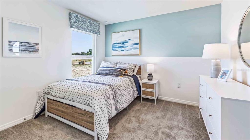 A bedroom features a bed with patterned bedding, a light blue accent wall, and carpet — 35489 SUNFLOWER HILL DRIVE, ZEPHYRHILLS, FL