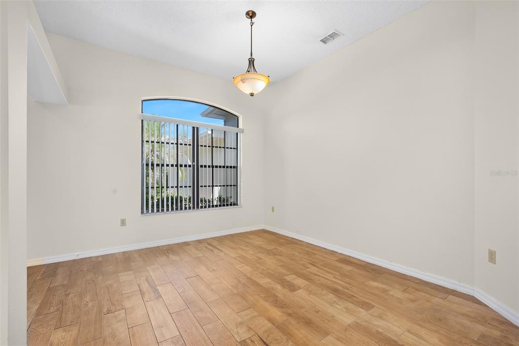 An empty room features light wood-look tile flooring, white walls, and an arched window — 1837 E GLANCY DRIVE, DELTONA, FL