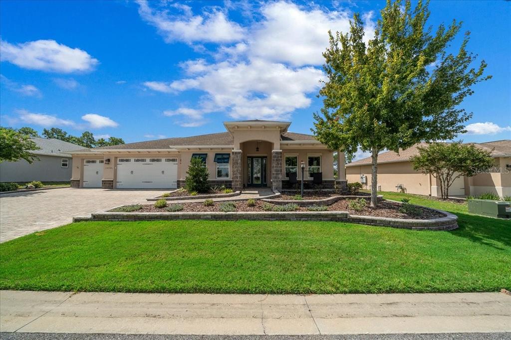A single-story house with a paved driveway, a three-car garage, and a landscaped front yard — 10346 SW 93RD PLACE, OCALA, FL